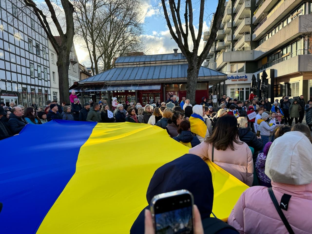 Eine große Ukrainefahne wird, auf dem Northeimer Marktplatz, von einer Menschenmenge getragen.